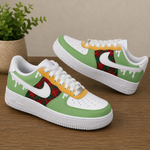 A pair of customized Nike Air Force 1 style sneakers with a green and white color scheme, featuring a red tartan plaid pattern on the Swoosh and heel area, yellow paint-drip accents, and white laces, displayed on a wooden tabletop with a potted plant in the background.