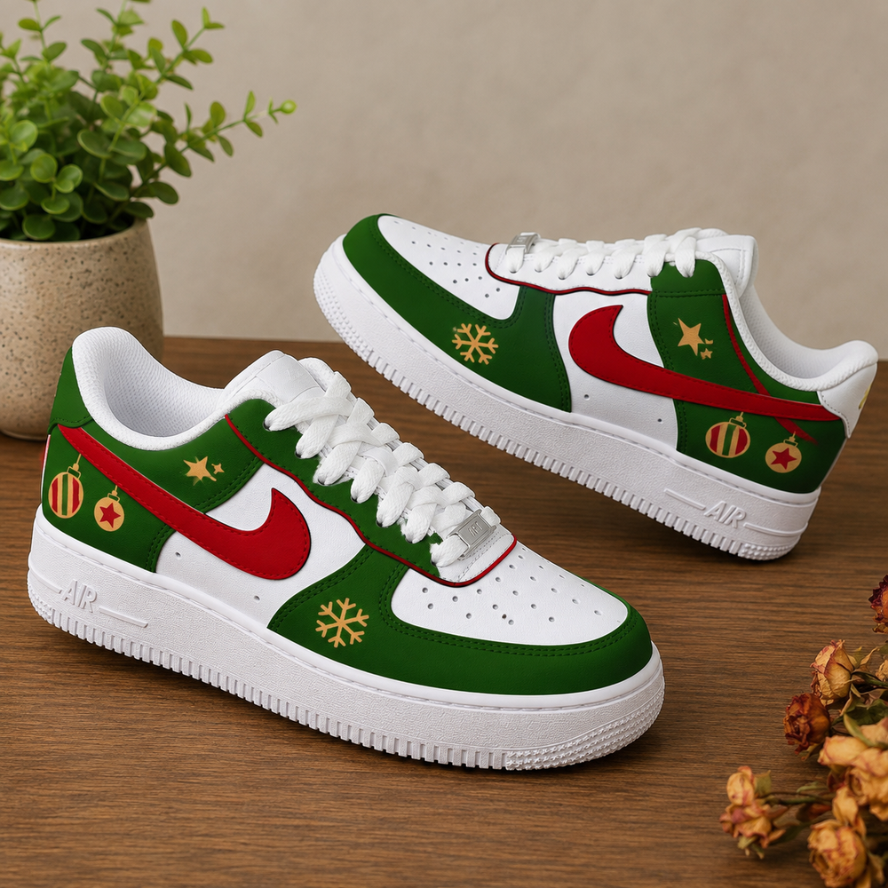 A pair of white Nike Air Force 1 style sneakers decorated with a Christmas theme, featuring green panels, a red Swoosh, gold snowflakes, and red-and-green ornament details, displayed on a wooden surface.