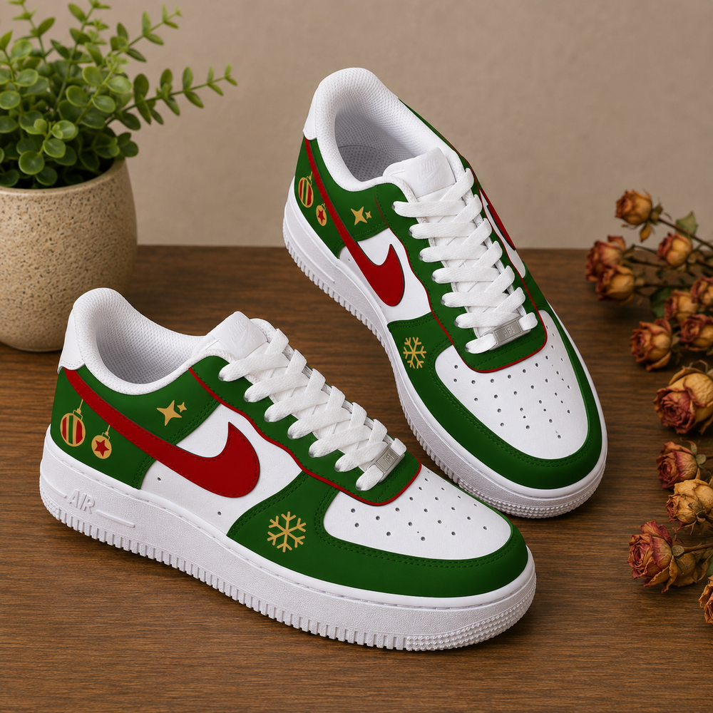 A pair of low-top Nike sneakers with a Christmas holiday theme, featuring green and white panels, red swooshes, gold snowflakes, and festive accents, displayed on a wooden surface with a potted plant and dried flowers.