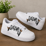 A pair of white low-top sneakers with black graffiti-style 'LUICEWORLD' lettering and small orange-and-black butterflies on the sides, displayed on a wooden surface with a potted plant in the background.