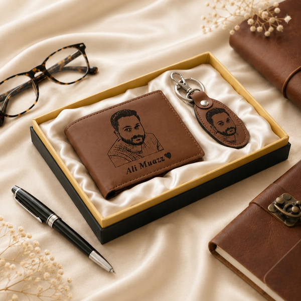 A personalized brown leather wallet and matching keychain set presented in a black gift box with cream satin lining. The wallet and oval keychain are engraved with a portrait of a man and the name 'Ali Muezz' with a small heart.